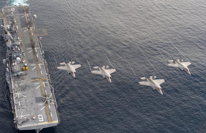 Four USMC-operated F-35B Lightning IIs fly over USS America (LHA-6) during the third shipboard deployment phase of the F-35 Developmental Test III (DT-III) on November 20, 2016. When needed, US Navy amphibious assault ships, like America, can embark up to 20 F-35Bs for an operational deployment.
